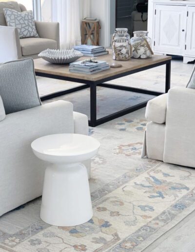 A living room with white furniture and a blue rug.